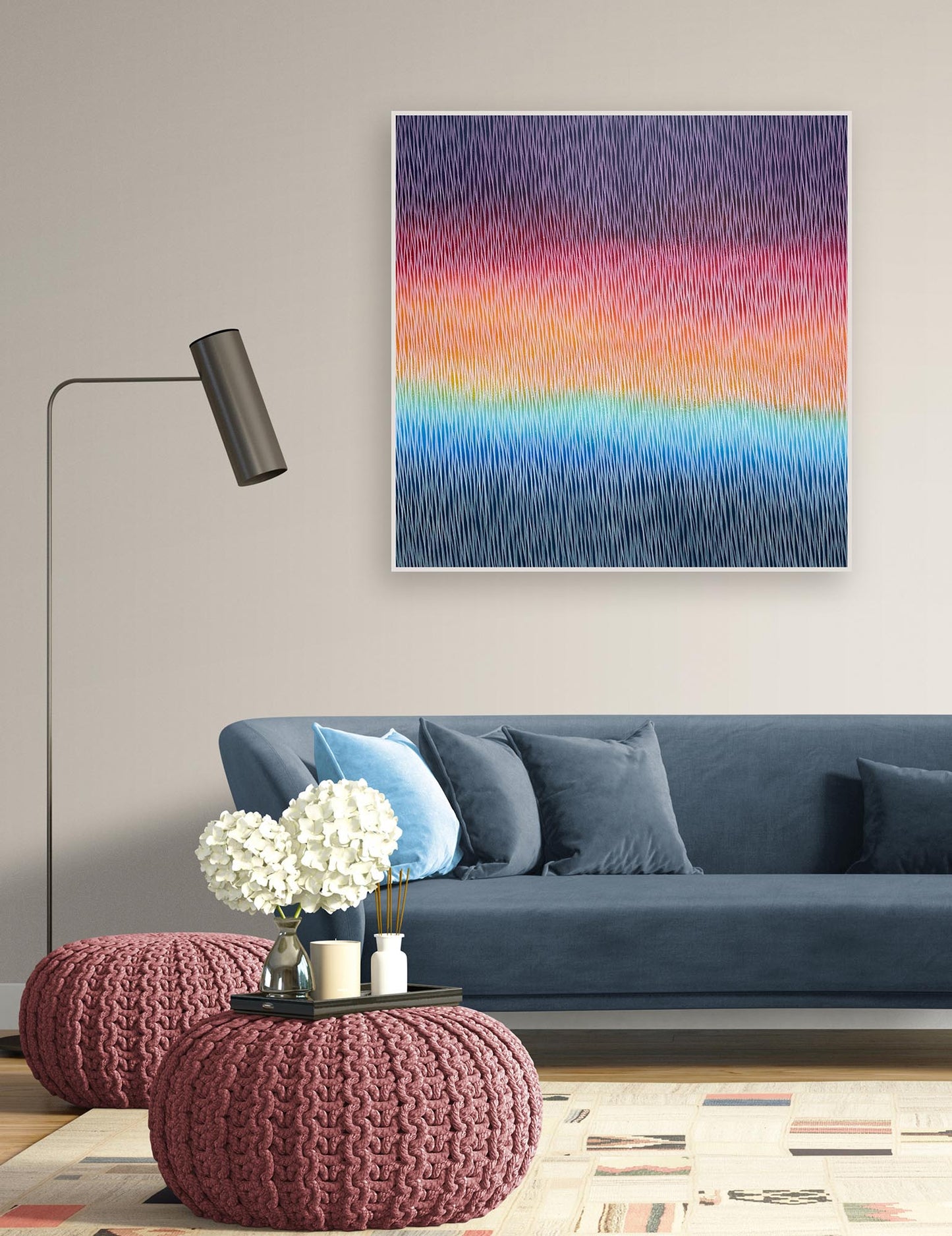 Living room with a blue sofa, pink poufs, and a colorful abstract painting on the wall.
