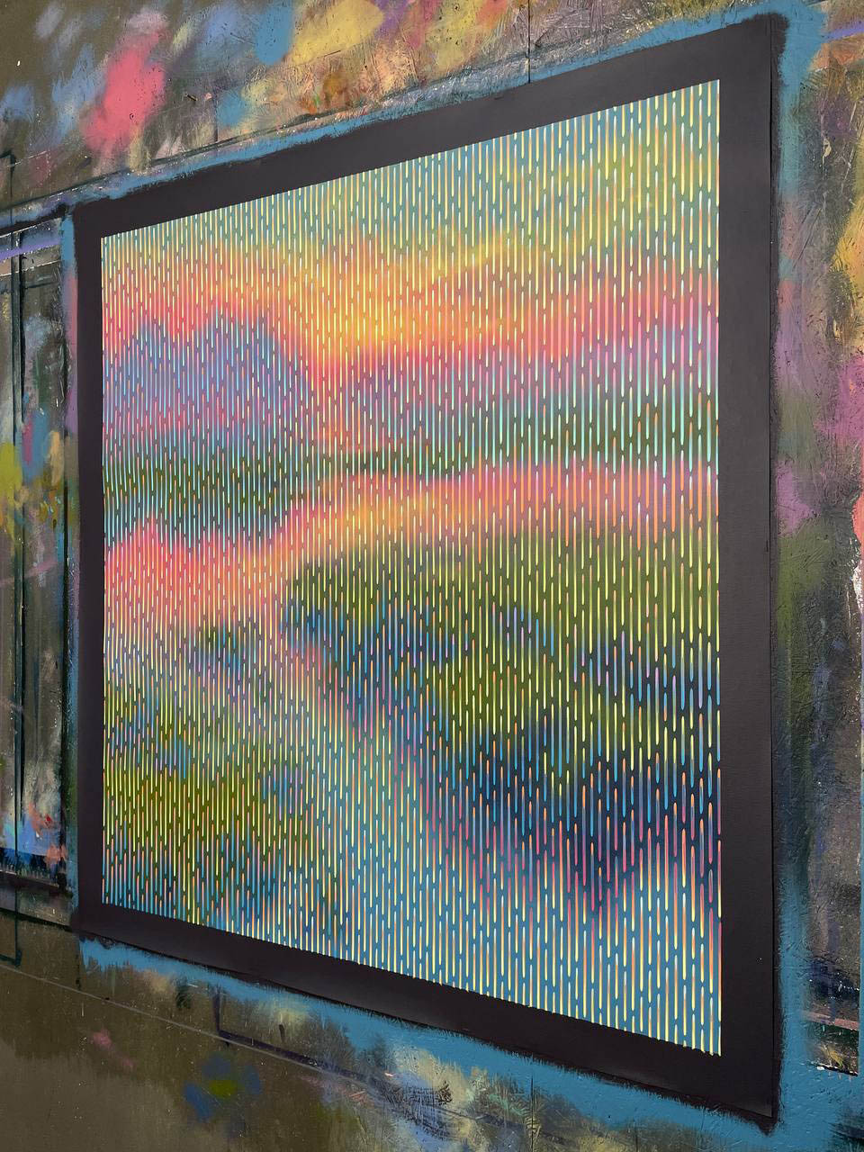 Colorful abstract art on a wall with a large screen displaying a similar pattern.